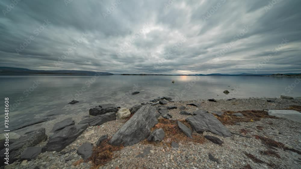 Stormy clouds move fast above the mirrorlike surface of the fjord and the pebble beach. A timelapse video. Stormy clouds move fast above the mirrorlike surface of the fjord and the pebble beach. A timelapse video.