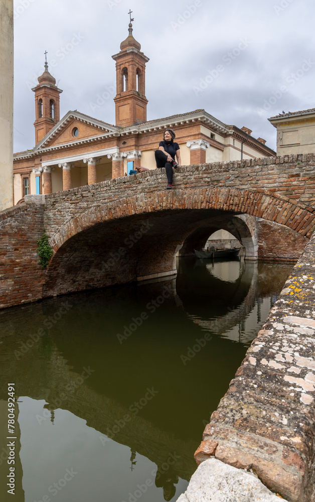 Woman on bridge in front of the cathedral San Cassiano in Comacchio in the province of Ferrara in the region of Emilia-Romagna in Italy