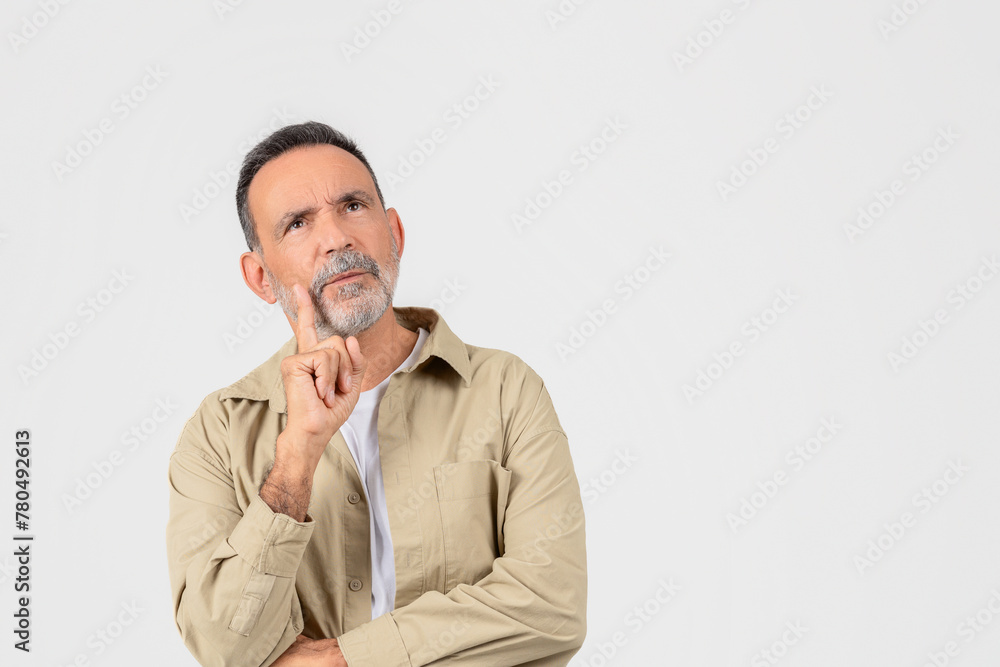 Mature man pondering with finger on cheek