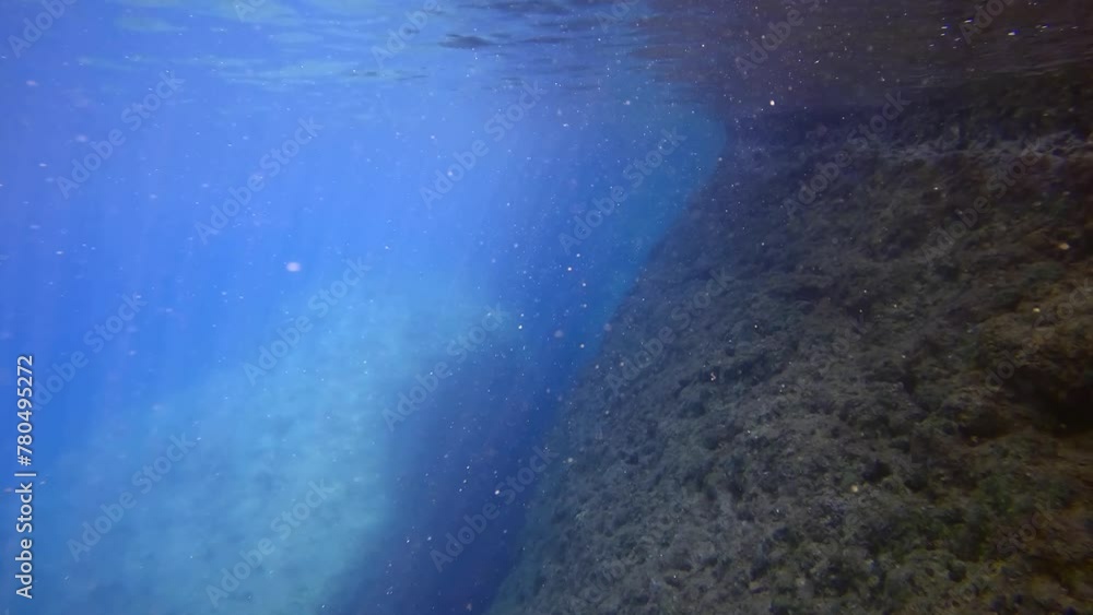 Bright sunrays in blue water, camera moving forwards underwater along rock, Slow motion. Underwater seascape of Mediterranean Sea, Greece Bright sunrays in blue water, camera moving forwards underwater along rock, Slow motion. Underwater seascape of Mediterranean Sea, Greece