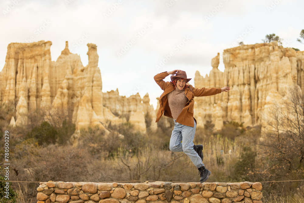 A woman is jumping on a rock bridge in the desert. The scene is serene and peaceful, with the woman's joyful expression and the beautiful landscape in the background