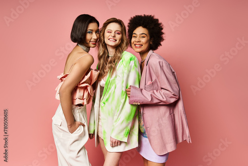 Three women of different ethnicities standing together, showcasing multicultural beauty against a pink studio backdrop. © LIGHTFIELD STUDIOS
