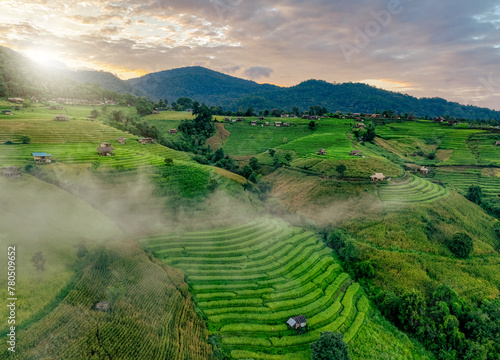 Landscape of rice terrace and hut with mountain range background and beautiful sunrise sky. Nature landscape. Green rice farm. Terraced rice fields. Travel destinations in Chiang Mai, Thailand.