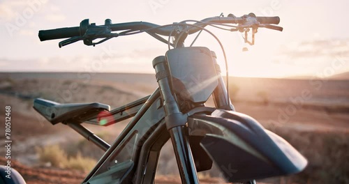 Sunset, desert and off road motorcycle for transport, adventure and machine on dune for competition. Extreme sport, mountain bike or motorbike on sand for challenge, power or race on dirt course. photo