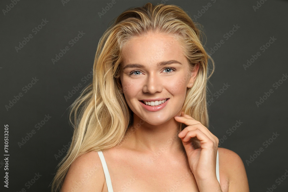 Fototapeta premium Good-looking young woman blonde with long healthy hair and fresh silky skin posing on black background. Fashion beauty studio portrait
