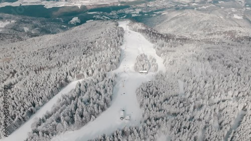 A serene, snow-covered forest stretches into the horizon, punctuated by a solitary chapel amidst the frosted trees. Areh, Pohorje, Slovenija photo