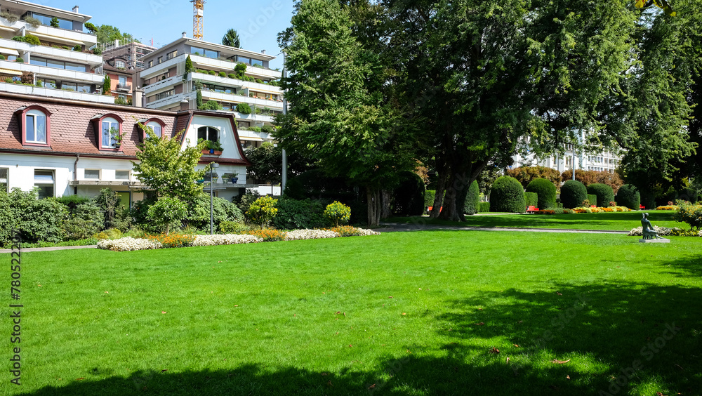 Park with green grass with trees and buildings
