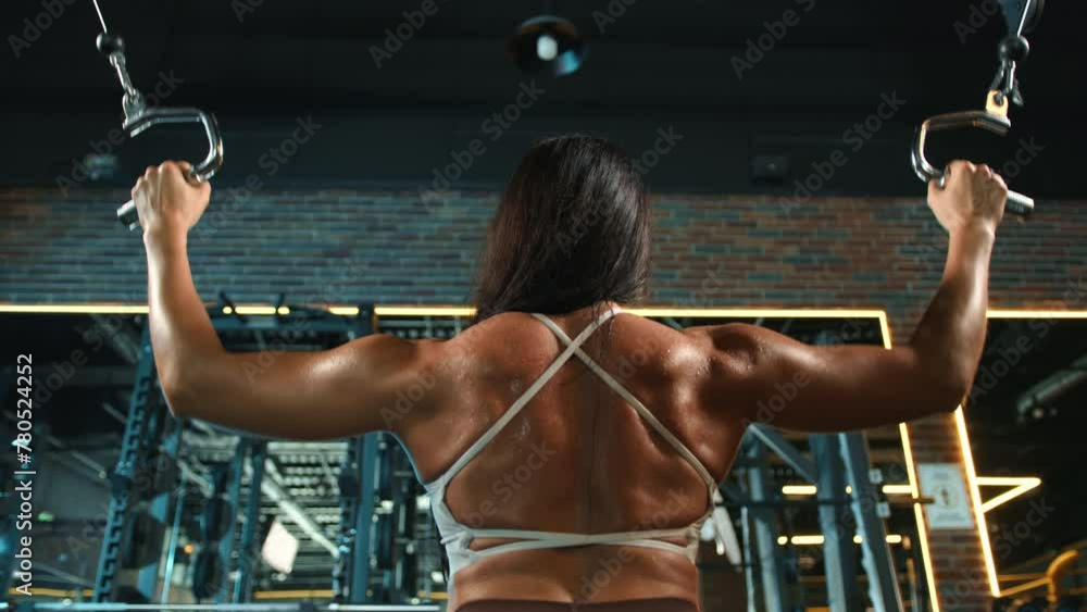 Rear view of a dedicated female athlete working out her back muscles on ...