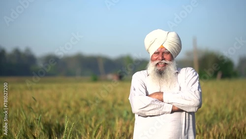 Portrait of happy senior indian punjab sikh farmer standing in wheat agriculture field with his arms cross, Rural india, copy space. photo