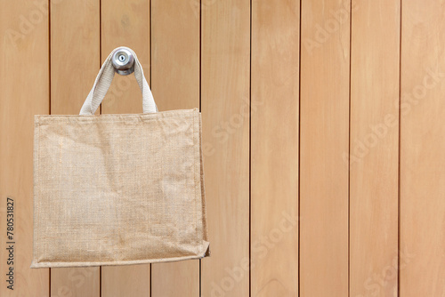 Nature eco-friendly grocery shopping bag, Jute tote bag with self handles hanging on wooden doll background