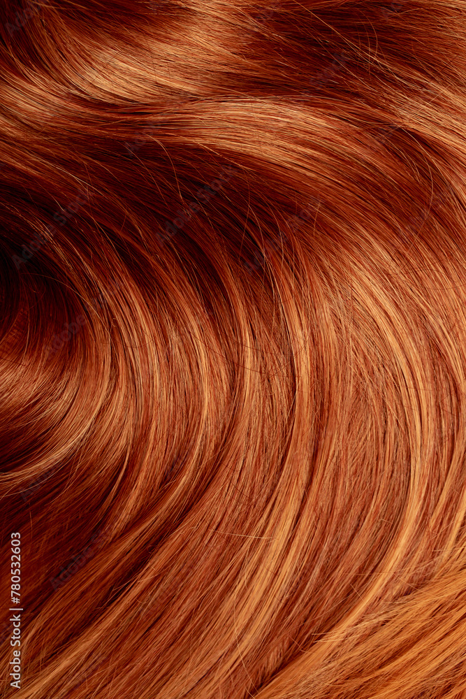 Fototapeta premium Red hair close-up as a background. Women's long orange hair. Beautifully styled wavy shiny curls. Hair coloring bright shades. Hairdressing procedures, extension.