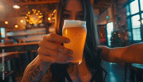 A girl holds a beer in her hands and make selfie in a craft pub. photo