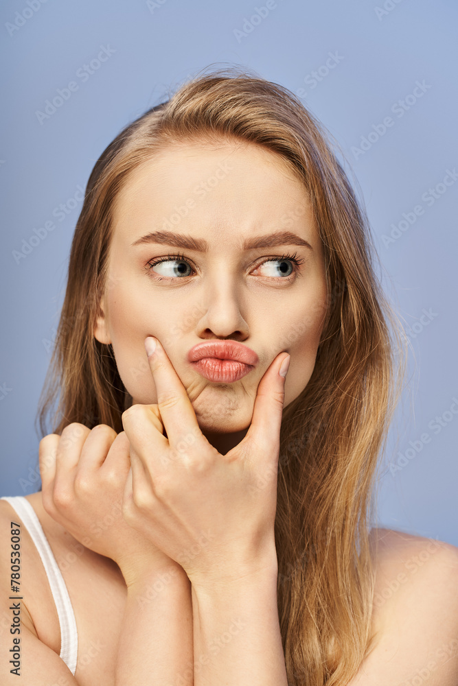 A young blonde woman with her hands covering her face, showing distress or anguish in a studio setting. A young blonde woman with her hands covering her face, showing distress or anguish in a studio setting.