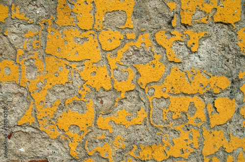 Old crumbling yellow plaster closeup