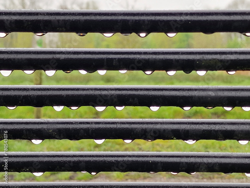 Abstract pattern of raindrops on bars of steel park bench