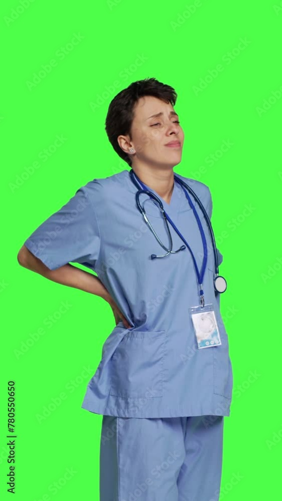 Side view Health specialist suffering from lower back pain after working after hours, feeling in pain and overworked with night shifts. Nurse having spine discomfort from scoliosis and bad posture Side view Health specialist suffering from lower back pain after working after hours, feeling in pain and overworked with night shifts. Nurse having spine discomfort from scoliosis and bad posture