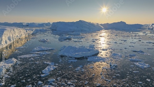 Bright sun melts pieces of the iceberg in Greenland. Aerial shot of iceberg pieces on sunny day, global warming and climate change concept © SJ Travel Footage