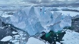Flying over giant iceberg near Ilulissat, Greenland. Iceberg pieces break off and fall into the water. Aerial arctic nature landscape, global warming and climate change concept