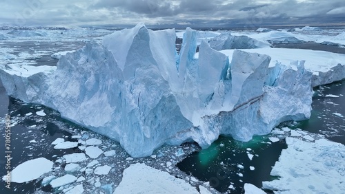 Flying over giant iceberg near Ilulissat, Greenland. Iceberg pieces break off and fall into the water. Aerial arctic nature landscape, global warming and climate change concept © SJ Travel Footage