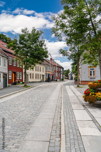 Traditional colorful houses line the cobblestone street of Øvre Bakklandet in Trondheim, Norway on a sunny summer day, tourist travel destination.