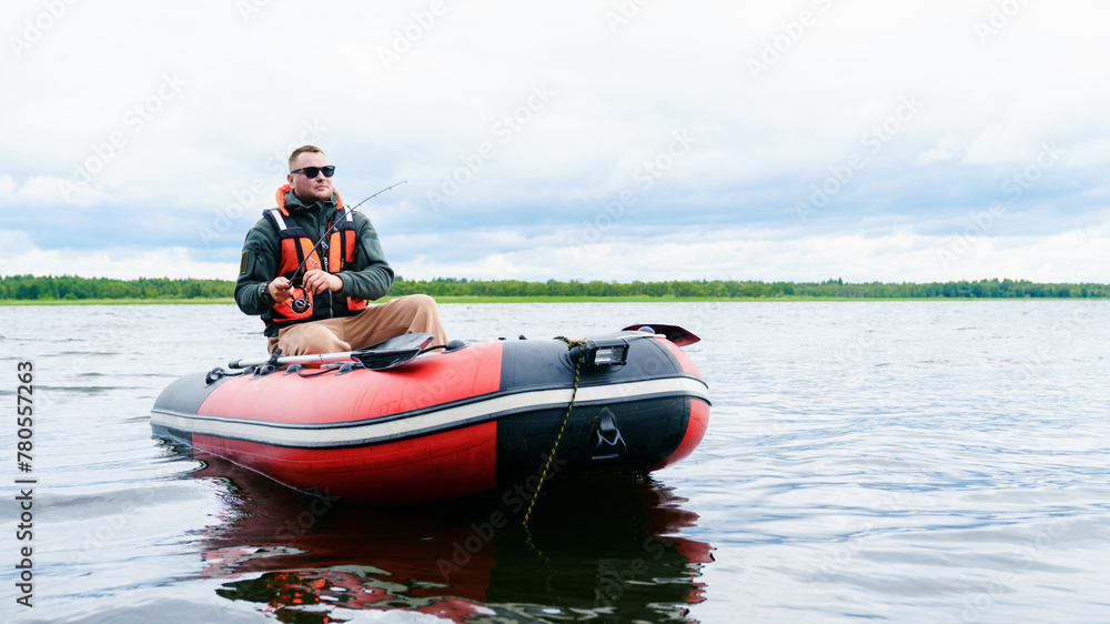A fisherman sits in a boat and fishes. View from the water. Clean lake water in summer