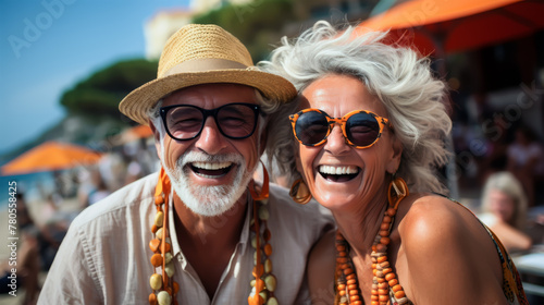 Retired elderly people enjoy the Holidays trip on the beach bar. Happy adult couple laughing out loud and enjoying a day of vacation on the beach