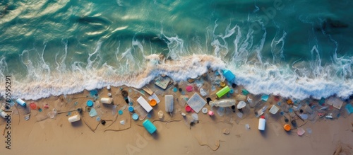 Polluting plastic items including bottles, cups, utensils, and straws, notably in oceans. Aerial perspective of sand.