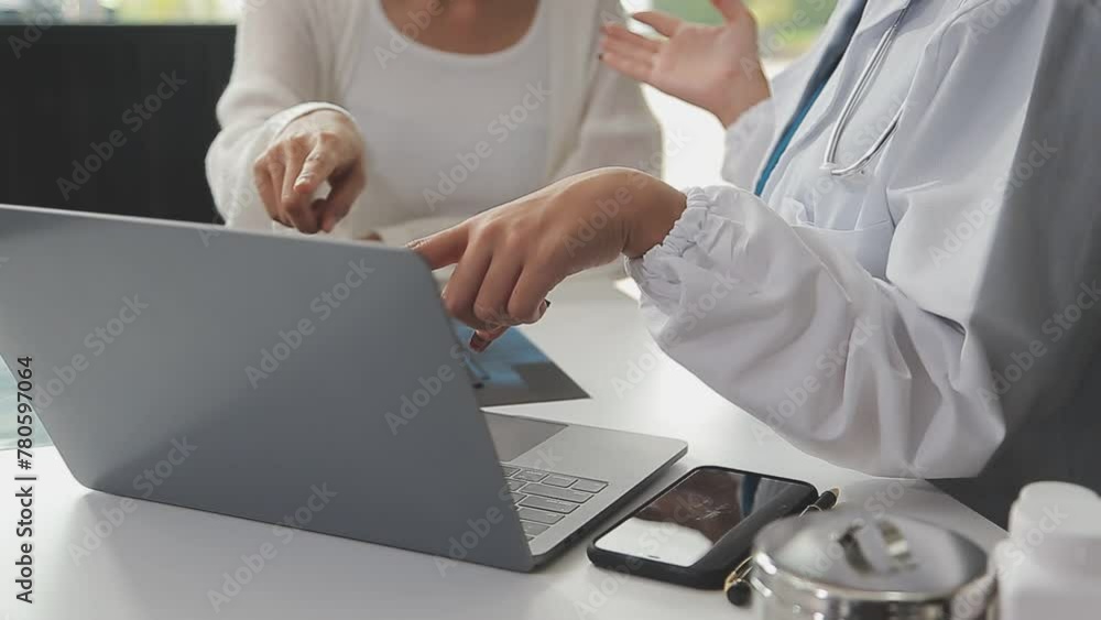 Serious female doctor using laptop and writing notes in medical journal sitting at desk. Young woman professional medic physician wearing white coat and stethoscope working on computer at workplace. Serious female doctor using laptop and writing notes in medical journal sitting at desk. Young woman professional medic physician wearing white coat and stethoscope working on computer at workplace.