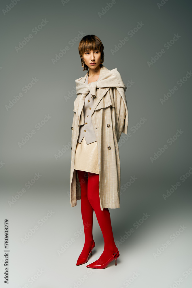 A stylish young woman with short hair poses confidently in a trench coat and vibrant red tights, exuding a sense of sophistication. A stylish young woman with short hair poses confidently in a trench coat and vibrant red tights, exuding a sense of sophistication.