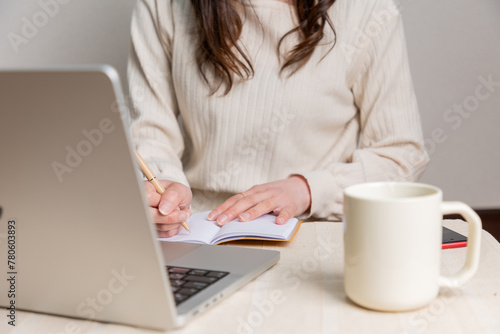 パソコンを見ながらメモをとる女性