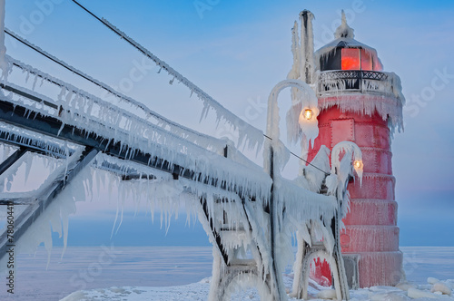 Winter landscape at dawn of the South Haven, Michigan lighthouse, pier, and catwalk coated in ice, Lake Michigan, USA photo