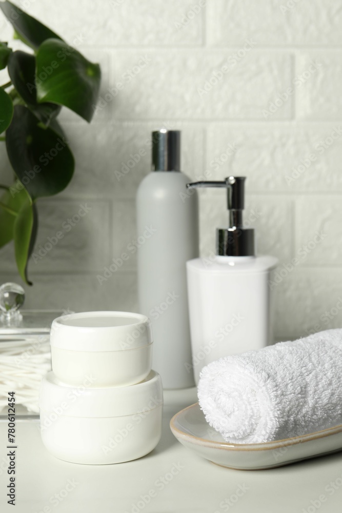Different bath accessories and personal care products on white table near brick wall