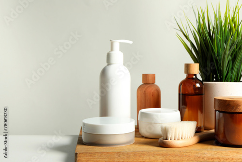 Different bath accessories and houseplant on white table against grey background, closeup. Space for text