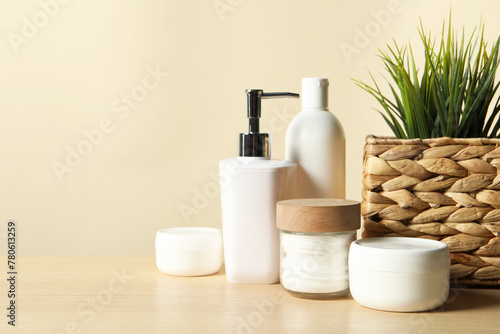 Different bath accessories and houseplant on wooden table against beige background, closeup. Space for text © New Africa