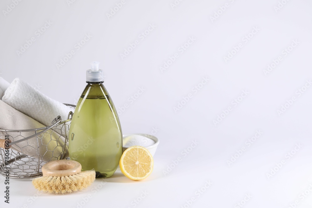 Bottle of cleaning product, brush, rags and lemon on light background Bottle of cleaning product, brush, rags and lemon on light background