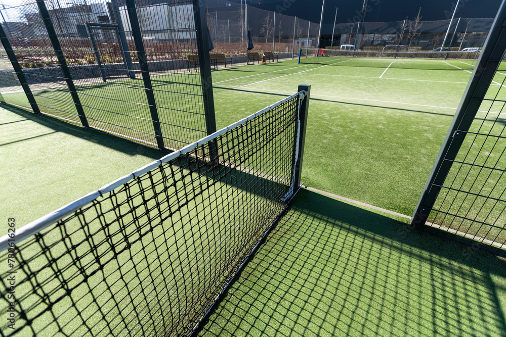 Landscaped areas of a residential development with a tennis court with high Plexiglas and metal fences Landscaped areas of a residential development with a tennis court with high Plexiglas and metal fences