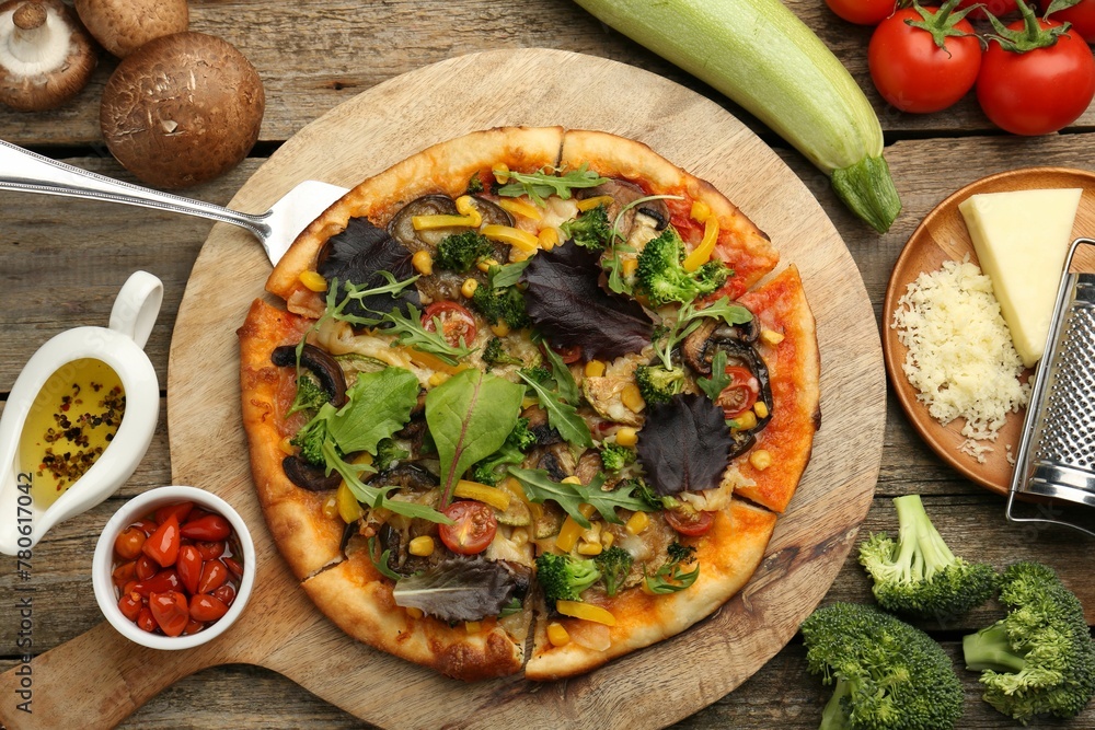 Delicious vegetarian pizza and ingredients on wooden table, flat lay