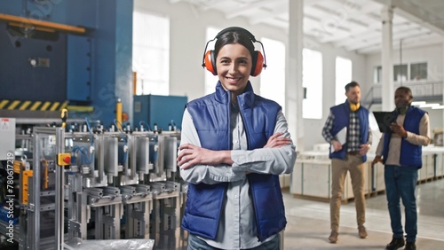 Happy satisfied contented glad working middle-aged pretty female industrial worker wearing special safety glasses and uniform. Emotional positive woman indoors at workplace.