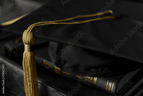 Black graduation cap with tassel on a book, close-up. © 7707601