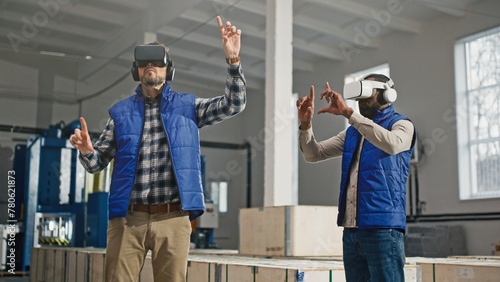 Multi-ethnic co-workers using Virtual Reality headsets for possible improvements in production. Digital device helping people in modern jobs. Moving hands while using VR to learn new concept.