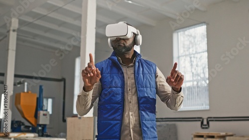 Close-up portrait of nice employed busy bearded African-American male during interesting work process. Innovative original worker using contemporary latest up-to-date VR device.