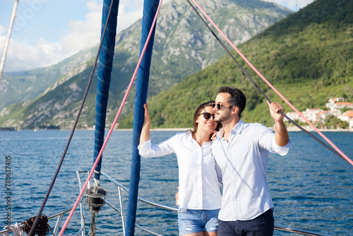 Happy couple in love traveling on yacht at sea. Tourists sailing, enjoying sunny summer vacation. Travelers hugging and relaxing. Intimate romantic date and holidays on sailboat. Lifestyle moment