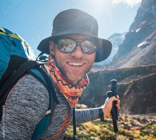 Portrait Young hiker backpacker man in sunglasses smiling at camera in Makalu Barun Park route during high altitude acclimatization walk. Mera peak trekking route, Nepal. Active vacation concept image
