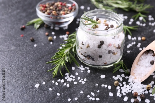 Salt with fresh rosemary and peppercorns on dark grey textured table