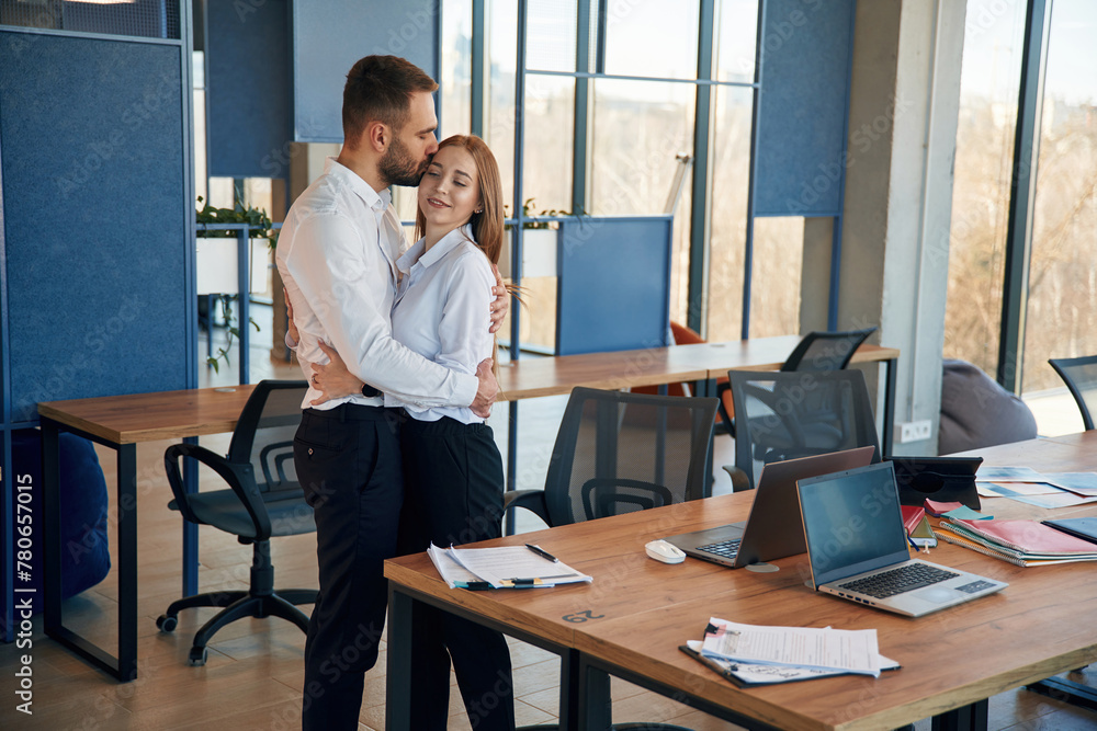 Embracing each other. Man and woman employees are working in the office Embracing each other. Man and woman employees are working in the office