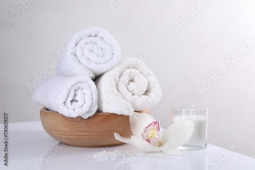 Spa composition with towels, orchid flower, candle and sea salt on white table