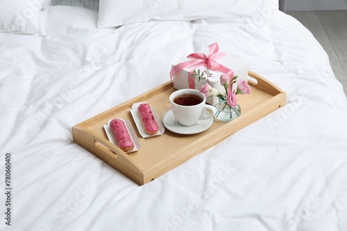 Tasty breakfast served in bed. Delicious eclairs, tea, gift box, flowers and card with phrase I Love You on tray