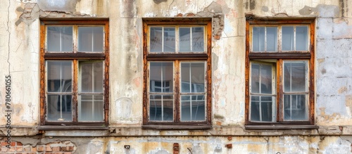 Part of an old building, three windows with wooden frames.