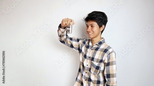 Handsome young Asian man happily taking photos using pocket camera photo