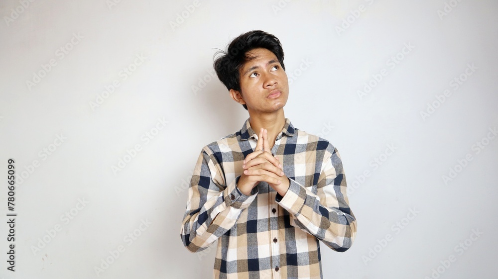 Thinking young Asian man posing looking up as if thinking about something or being confused about choosing Thinking young Asian man posing looking up as if thinking about something or being confused about choosing